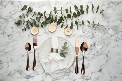 Beautiful place setting with candles and eucalyptus on white marble table, flat lay