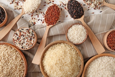 Photo of Flat lay composition with brown and other types of rice on wooden background