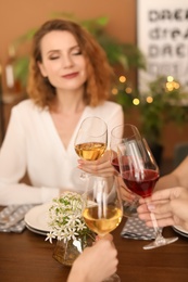 Young people with glasses of delicious wine at table