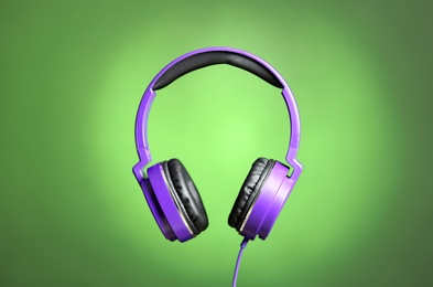 Stylish headphones with pads on color background