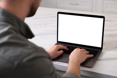 Photo of Man working on laptop at white marble table indoors, closeup