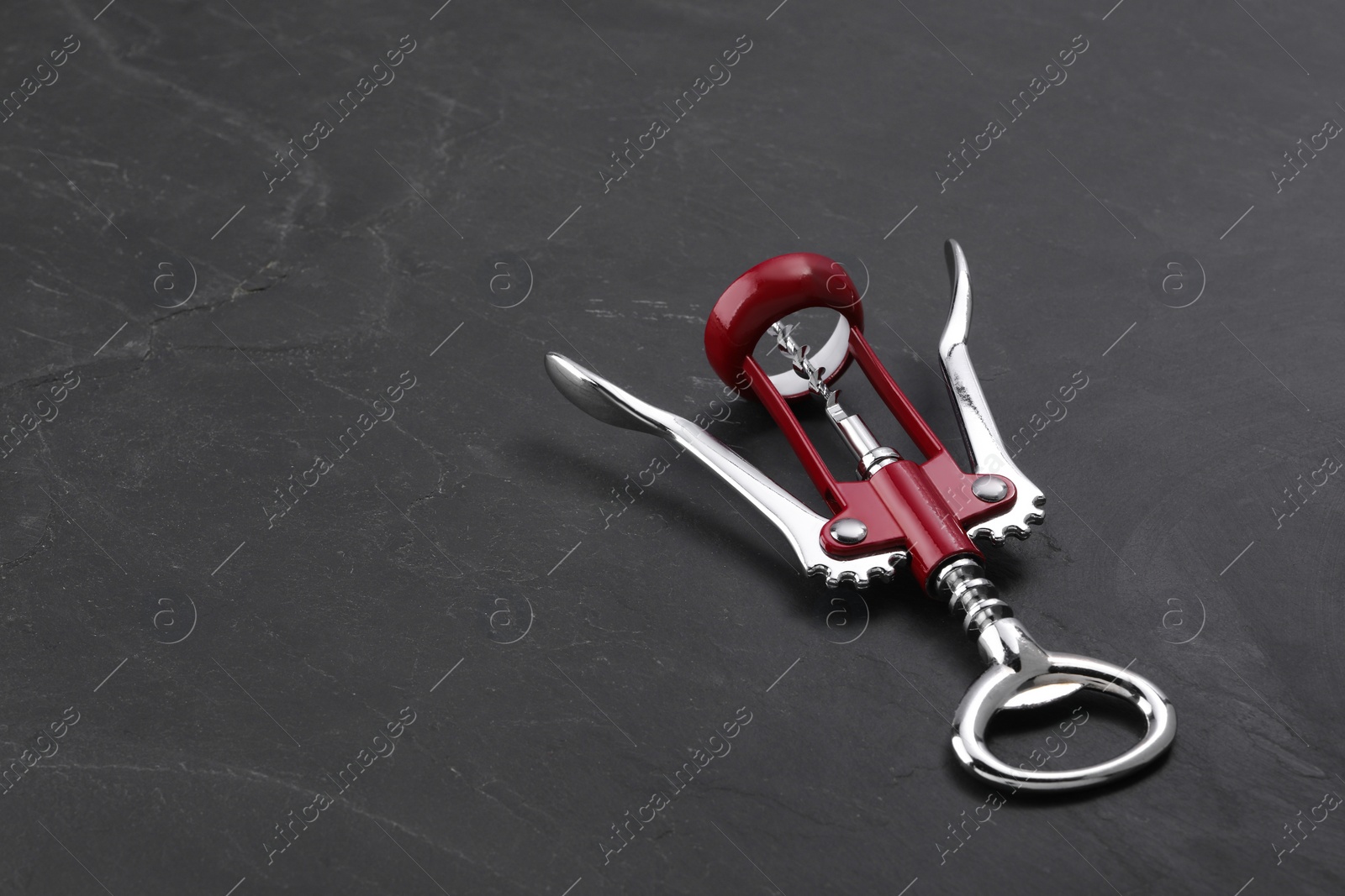 Photo of One wing corkscrew on grey textured table. Space for text