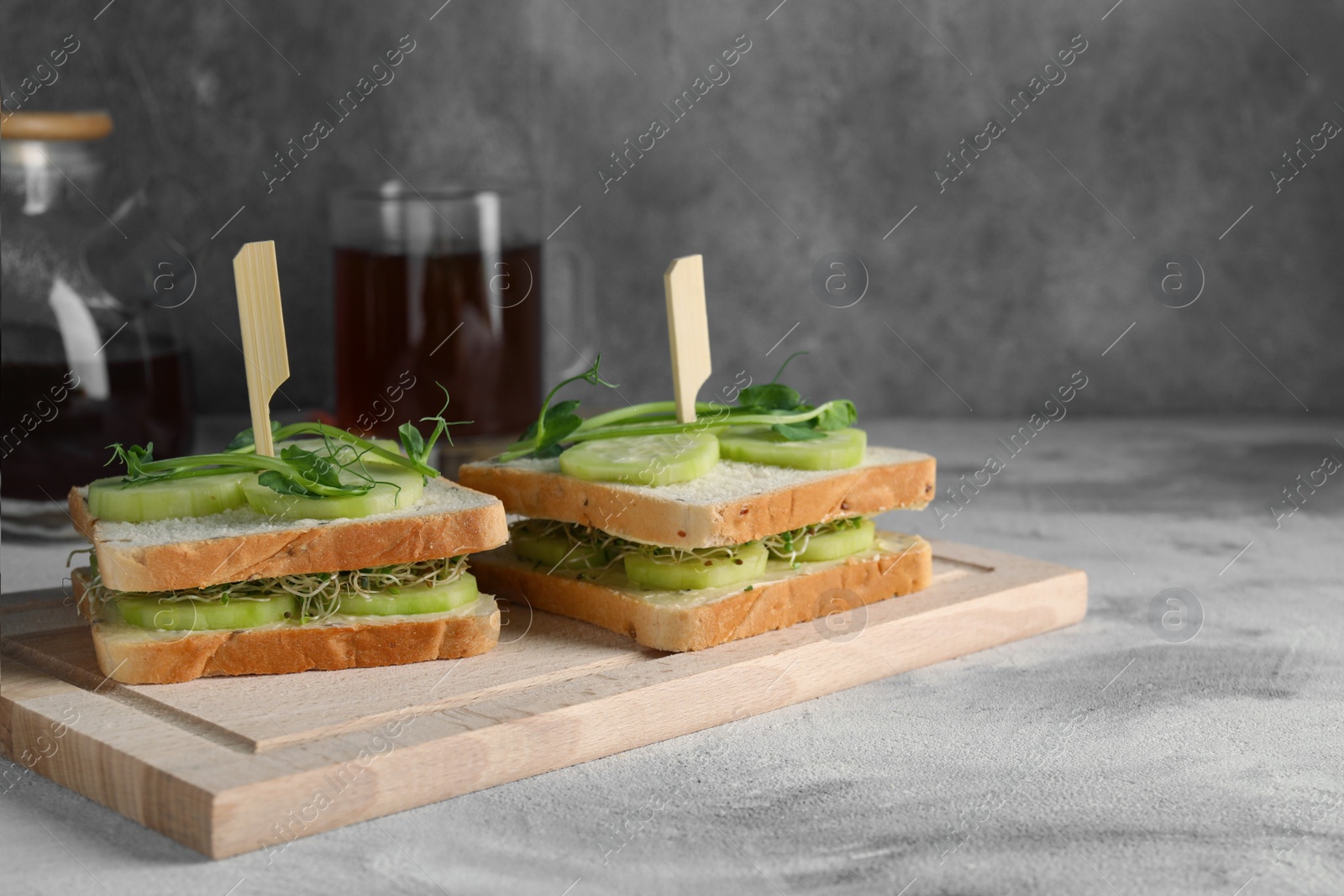 Photo of Tasty sandwiches with cucumber and microgreens on textured table. Space for text