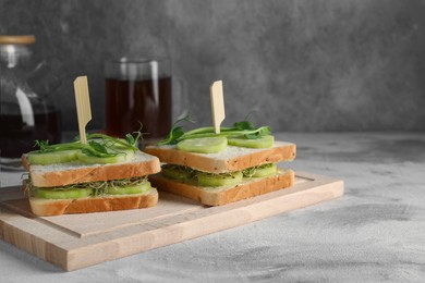 Tasty sandwiches with cucumber and microgreens on textured table. Space for text