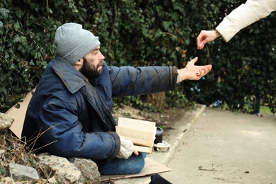 Photo of Woman giving alms to poor homeless man on street