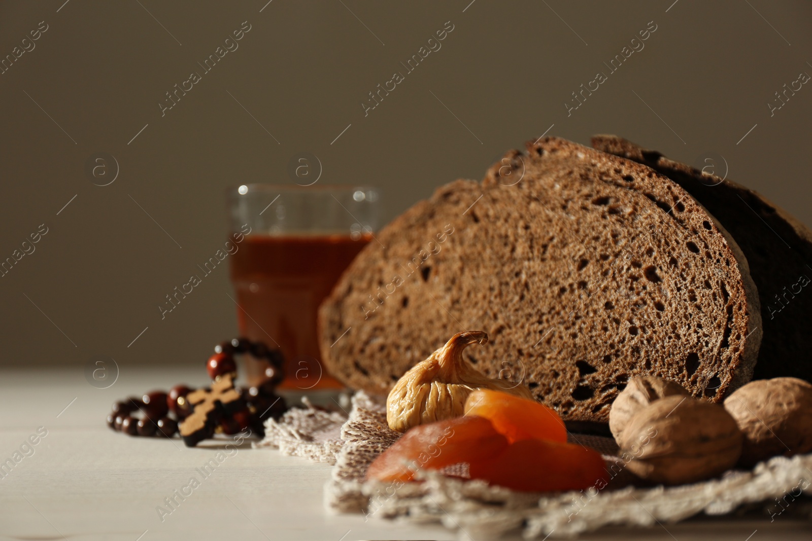 Photo of Rosary beads, dried fruits, walnuts, bread and drink on table. Lent season