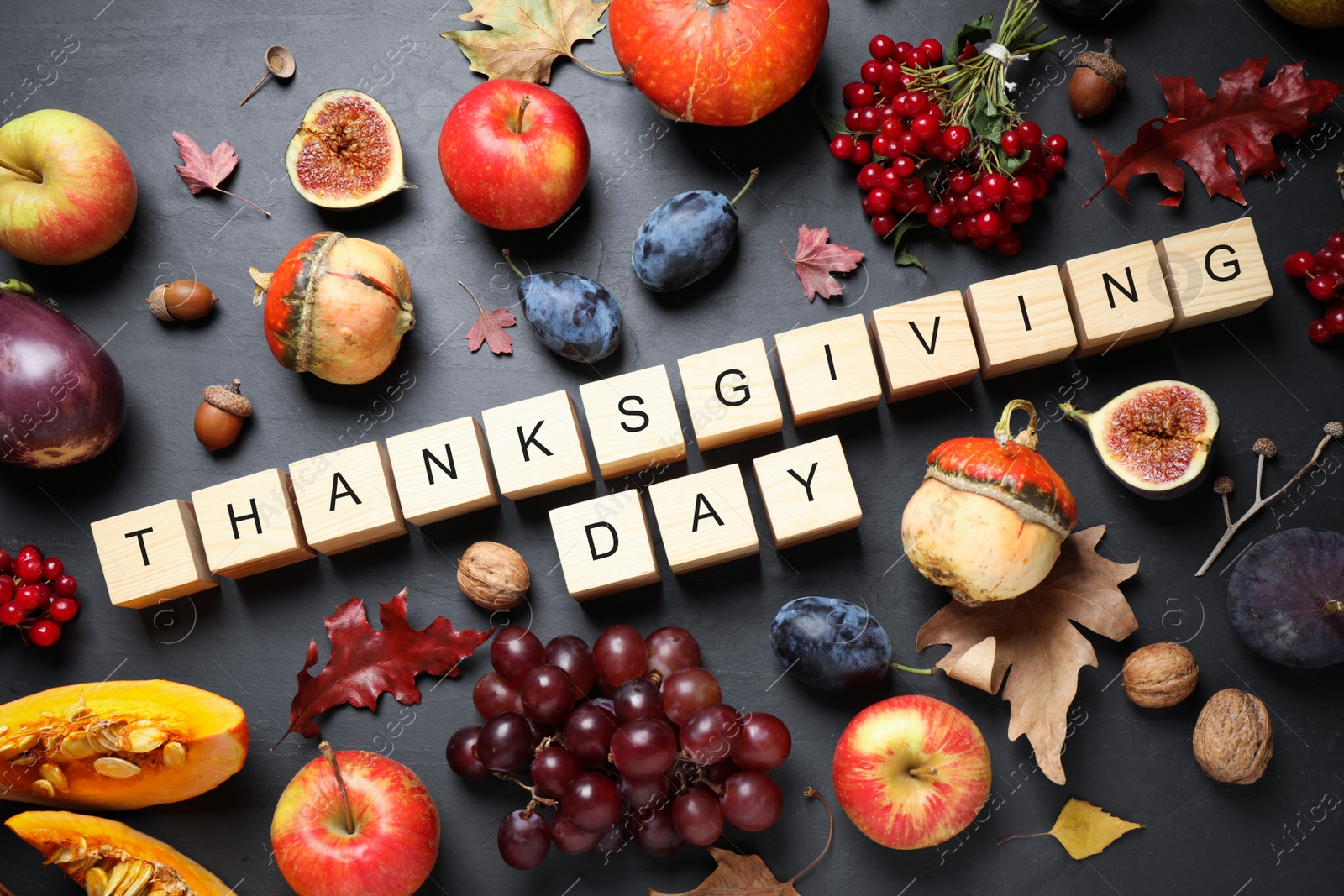 Photo of Cubes with phrase THANKSGIVING DAY, autumn fruits and vegetables on dark background, flat lay. Happy holiday