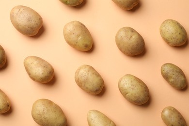 Photo of Fresh raw potatoes on pale orange background, flat lay