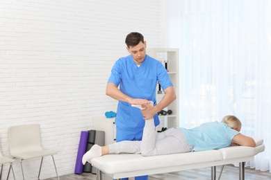 Photo of Physiotherapist working with patient in clinic. Rehabilitation therapy