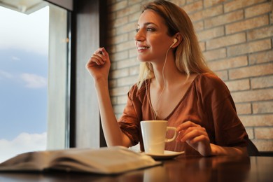 Woman listening to audiobook at table in cafe