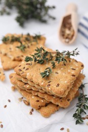 Photo of Cereal crackers with flax, sesame seeds and thyme on white table, closeup