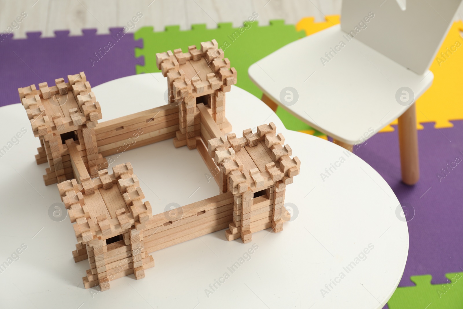 Photo of Wooden fortress on white table indoors. Children's toy