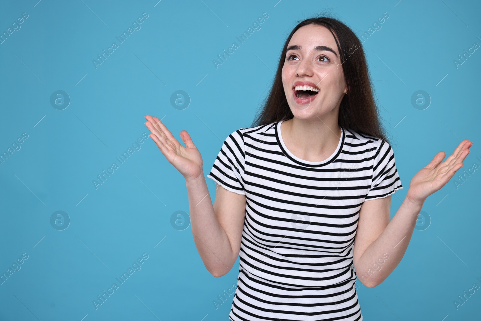 Photo of Portrait of happy surprised woman on light blue background. Space for text