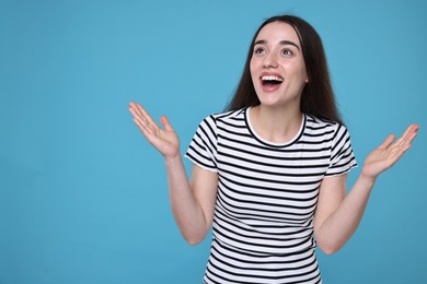 Photo of Portrait of happy surprised woman on light blue background. Space for text