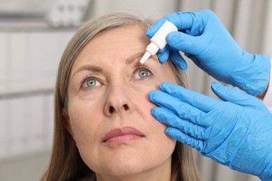 Photo of Medical drops. Doctor dripping medication into woman's eye indoors