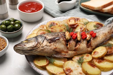 Photo of Plate with delicious roasted sea bass fish and potatoes on table, closeup