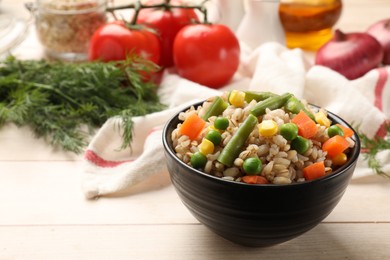 Photo of Delicious pearl barley with vegetables in bowl on wooden table, closeup. Space for text