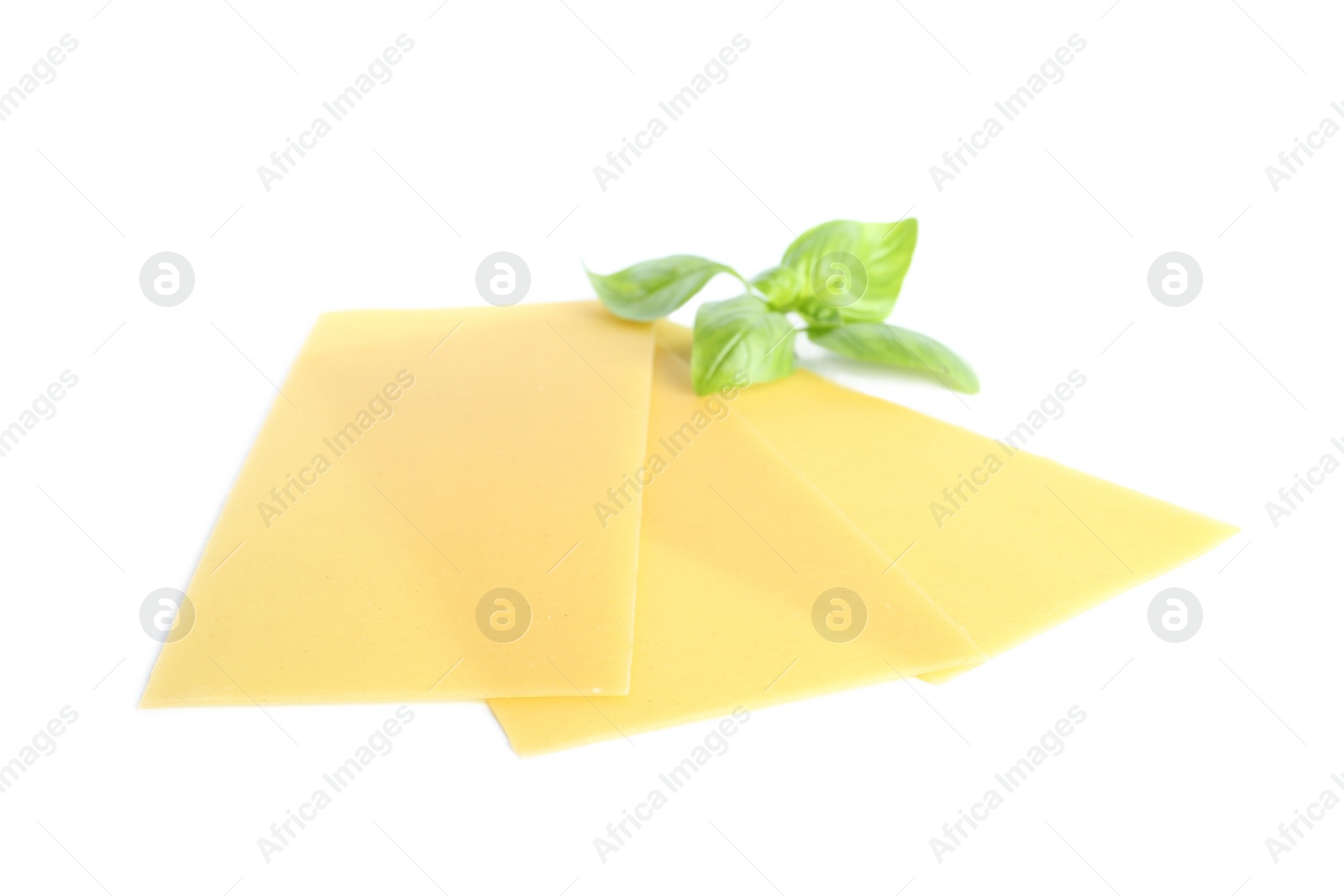 Photo of Uncooked lasagna sheets and basil on white background
