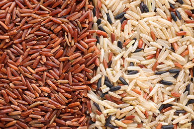 Photo of Mix of different brown rice as background, top view