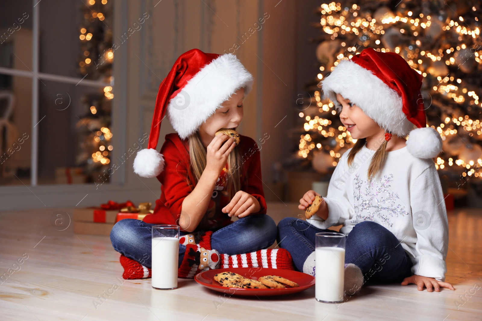 Photo of Cute little children with milk and cookies at home. Christmas time