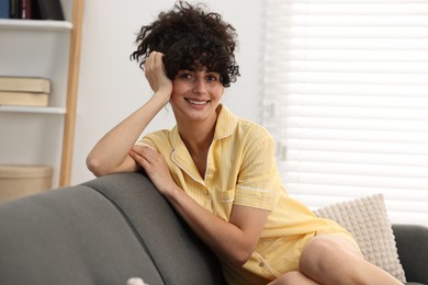 Beautiful young woman in stylish pyjama on sofa at home