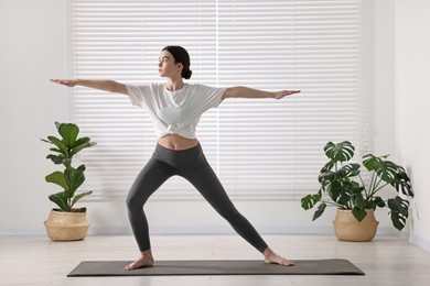 Photo of Girl practicing warrior asana in yoga studio. Virabhadrasana pose