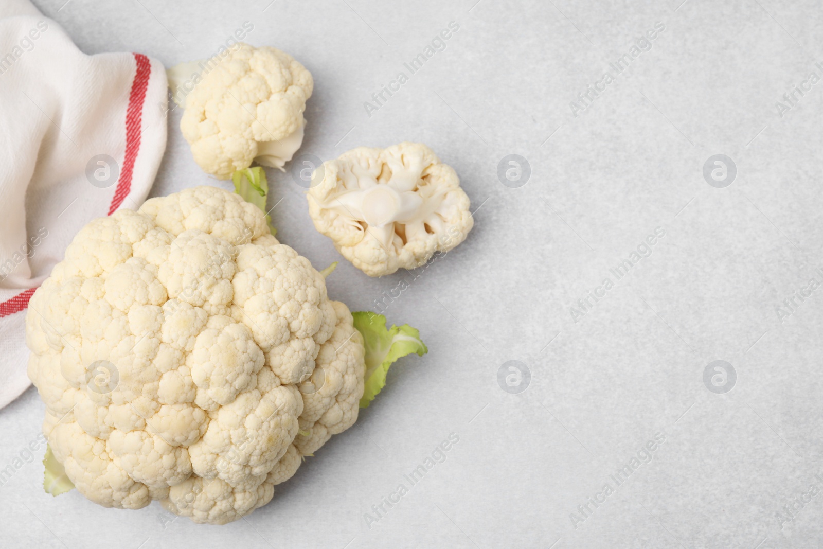 Photo of Cut fresh raw cauliflower on light grey table, flat lay. Space for text