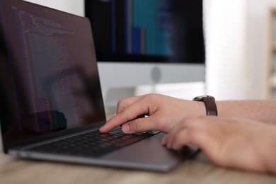 Photo of Programmer working with laptop at desk in office, closeup