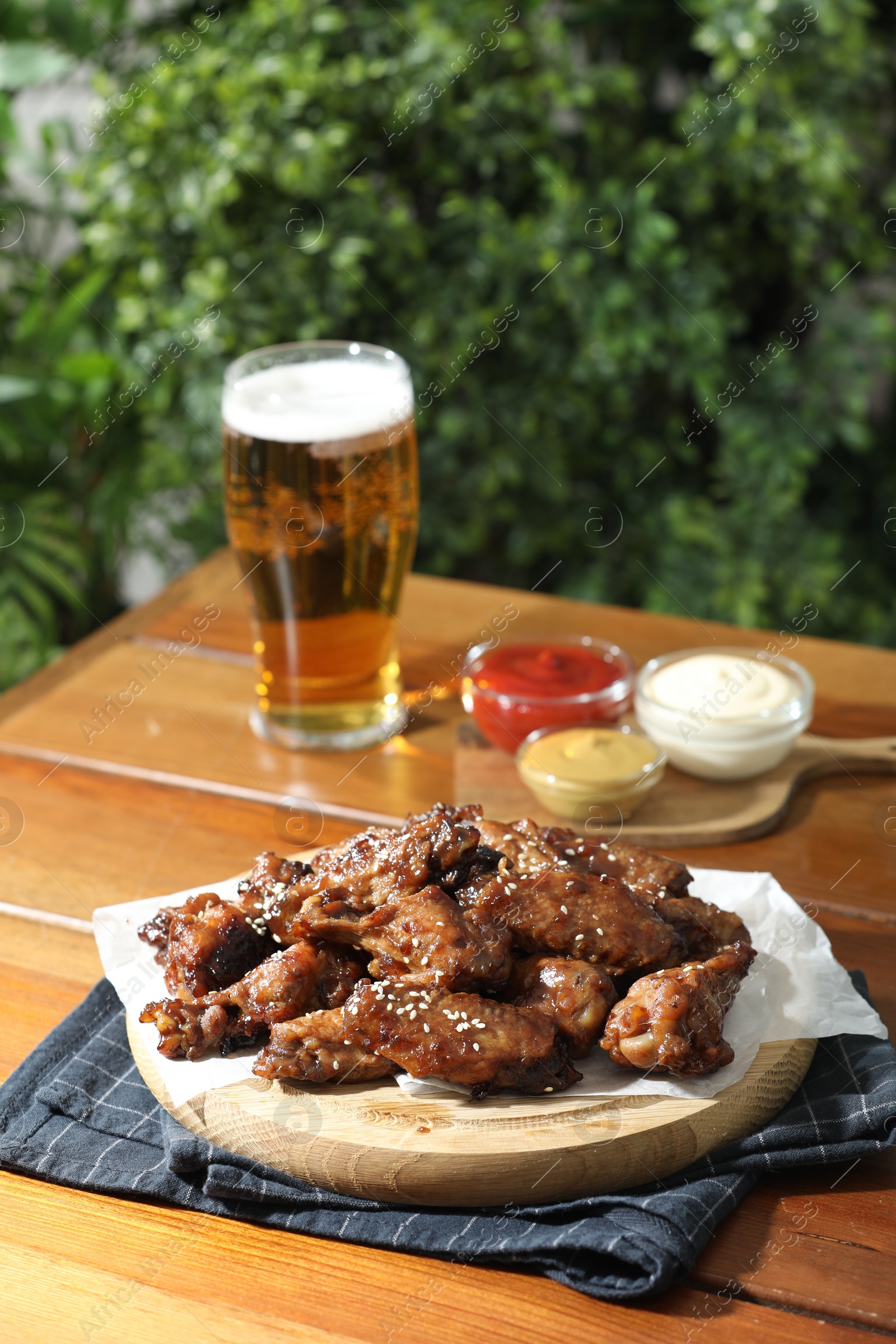 Photo of Tasty roasted chicken wings served with beer on wooden table