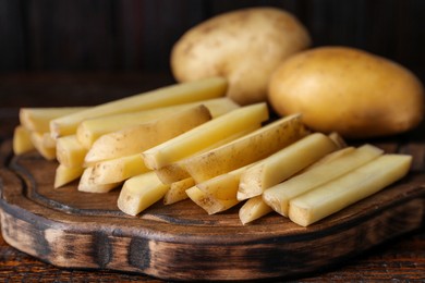 Photo of Whole and cut raw potatoes on wooden table, closeup