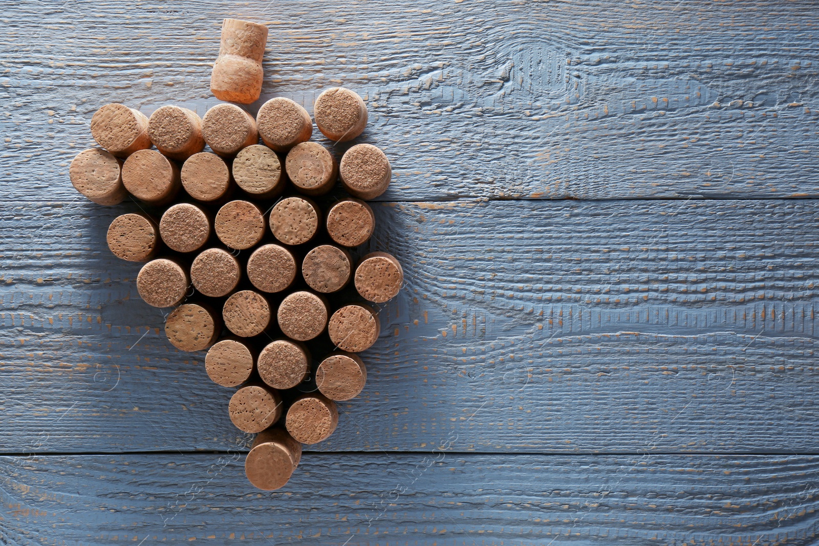 Photo of Grape made of wine bottle corks on grey wooden table, top view. Space for text