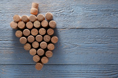 Photo of Grape made of wine bottle corks on grey wooden table, top view. Space for text