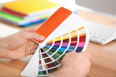 Designer with paint color palette samples at table, closeup