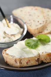 Photo of Pieces of bread with cream cheese and basil leaves on table, closeup