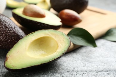 Whole and cut avocados on grey table, closeup