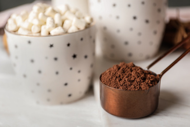 Photo of Cocoa powder in scoop and hot drink on white wooden table