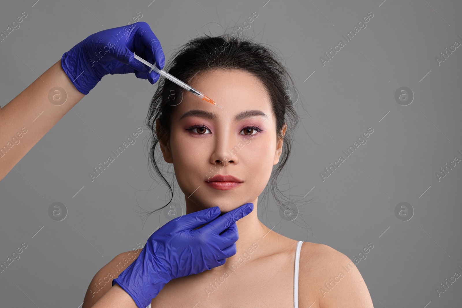 Photo of Woman getting facial injection on grey background