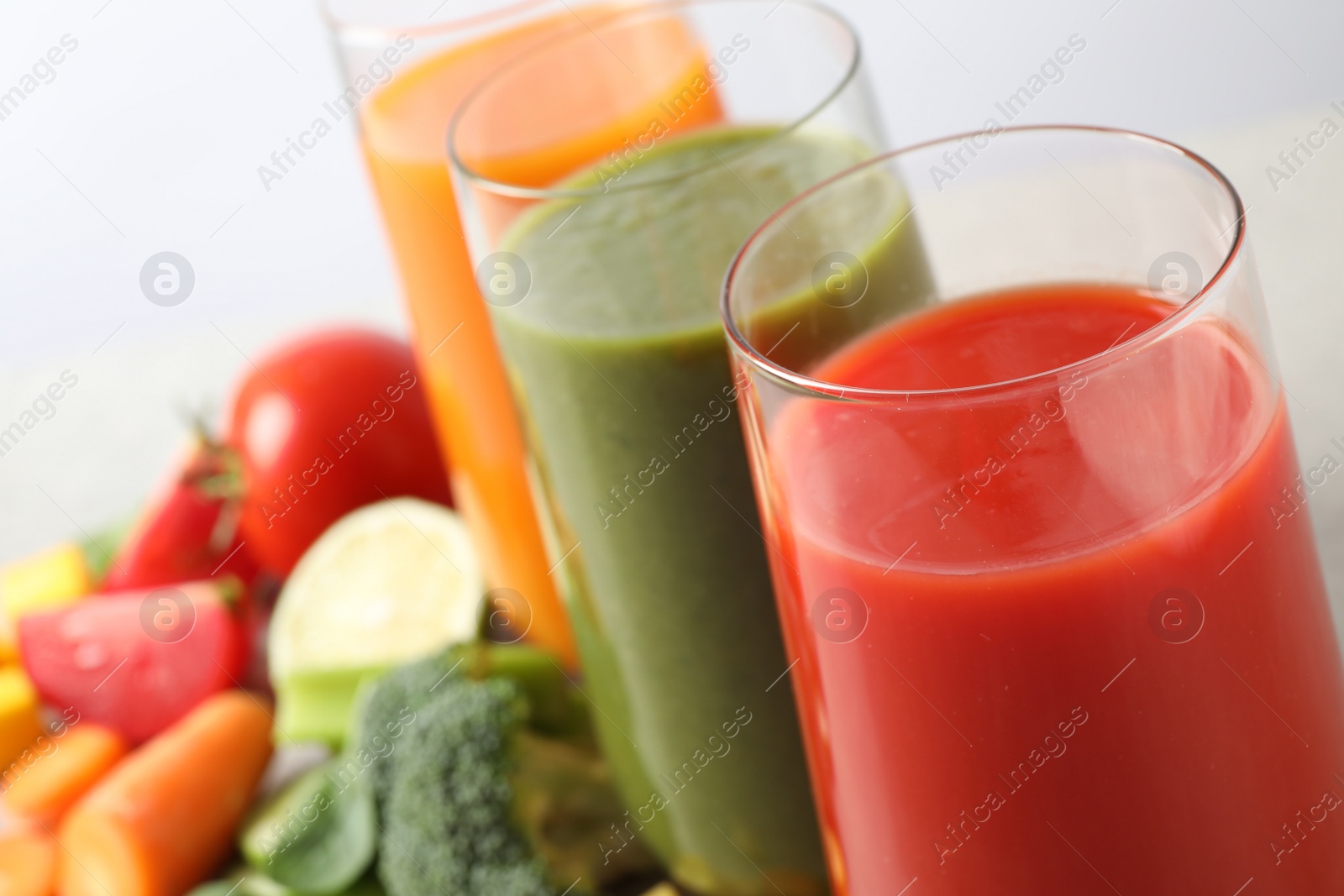 Photo of Different tasty juices in glasses on white background, closeup. Space for text