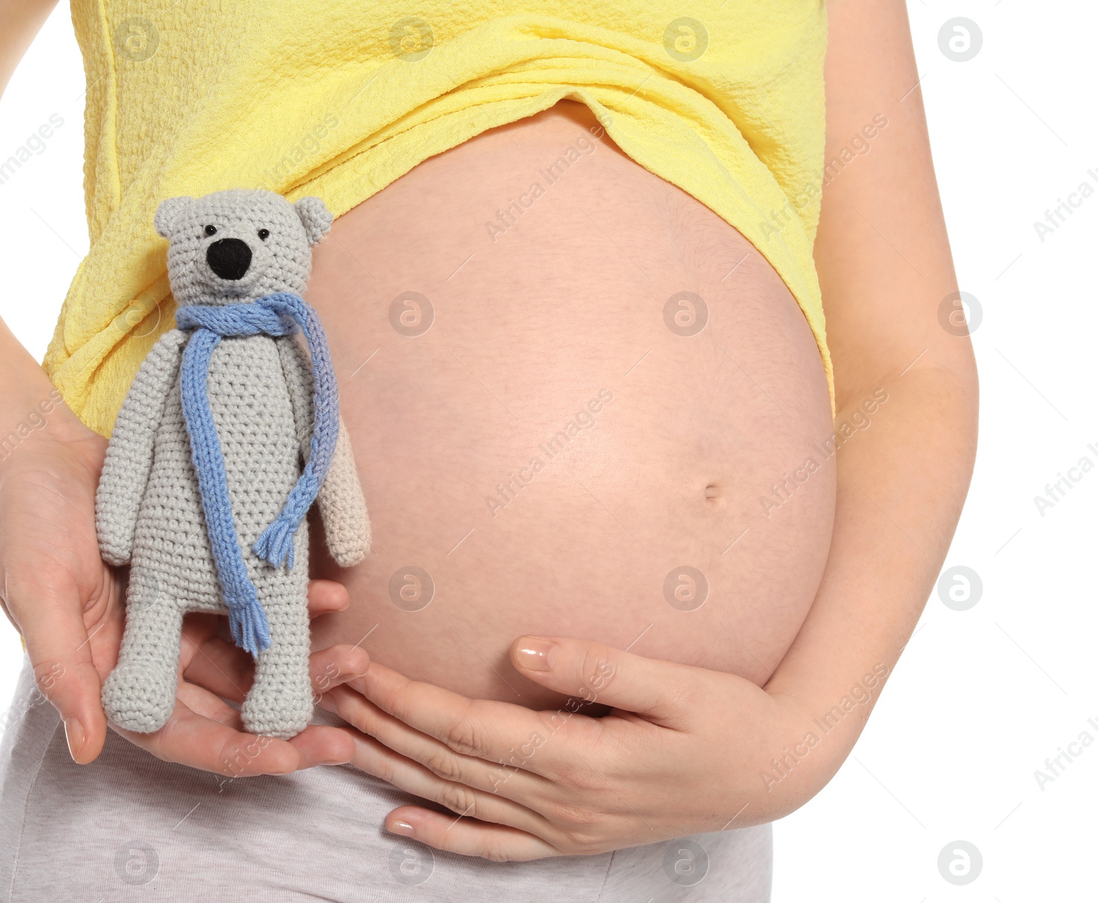 Photo of Pregnant woman holding soft toy near tummy on white background