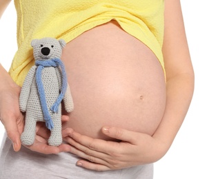 Photo of Pregnant woman holding soft toy near tummy on white background