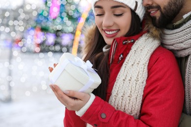 Photo of Happy young couple with gift box at winter fair. Christmas celebration