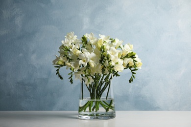 Photo of Beautiful freesia flowers in vase on white table