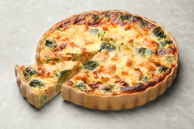 Photo of Delicious homemade quiche with salmon and broccoli on light gray table