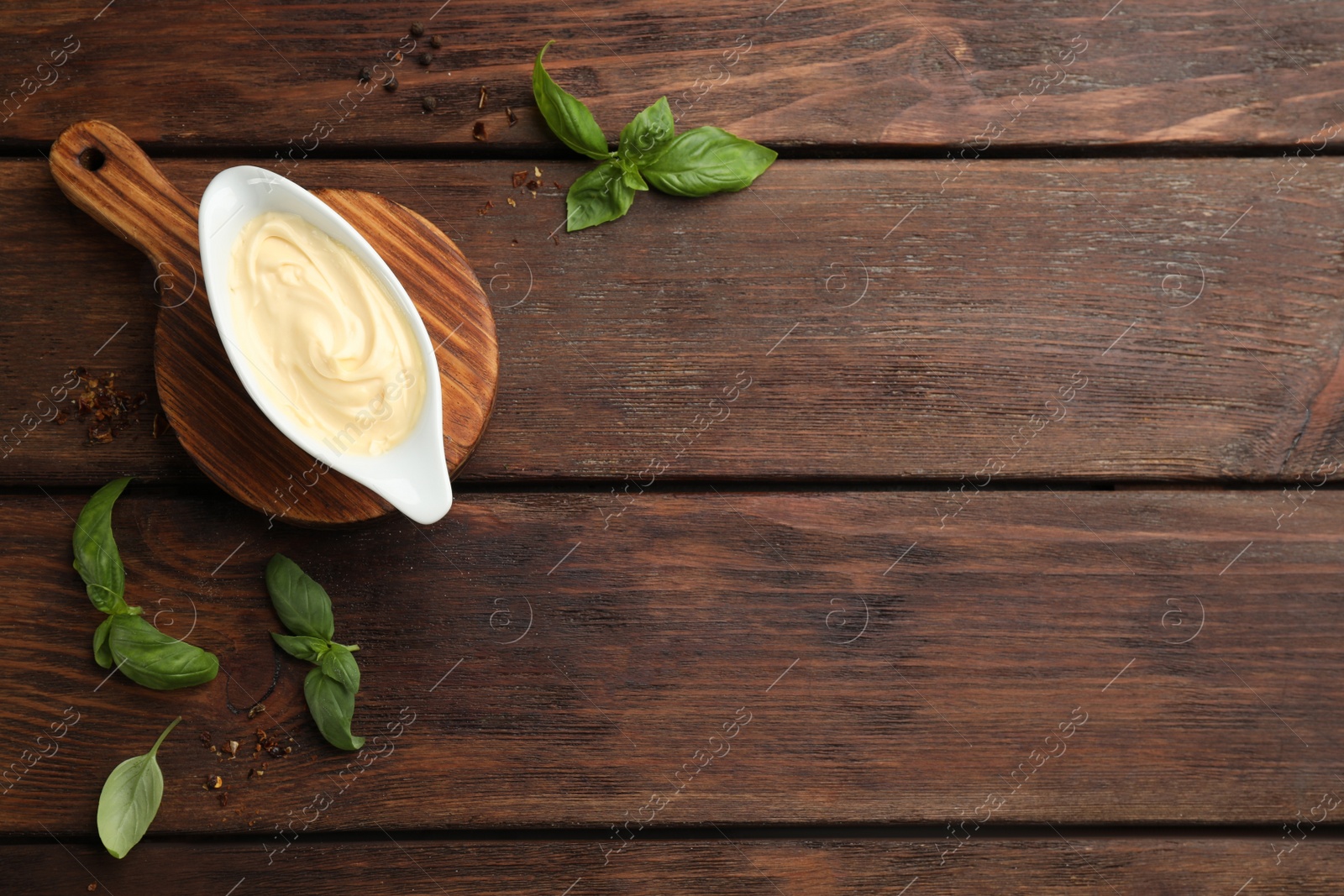 Photo of Tasty sauce in gravy boat, basil leaves and spice on wooden table, flat lay. Space for text