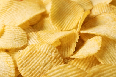 Pile of crispy potato chips as background, closeup