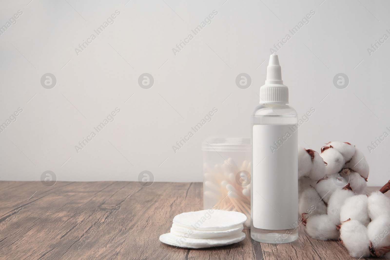 Photo of Composition with makeup remover and cotton flowers on wooden table against white background, space for text