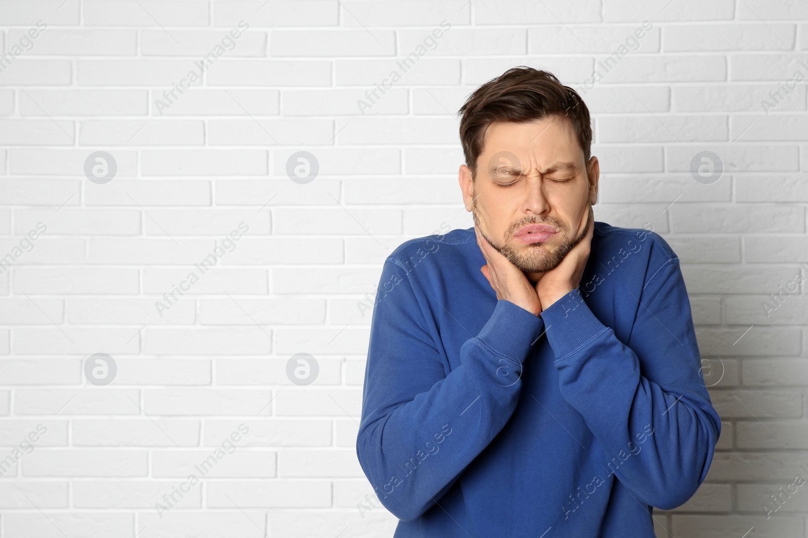 Photo of Man suffering from cough near brick wall. Space for text