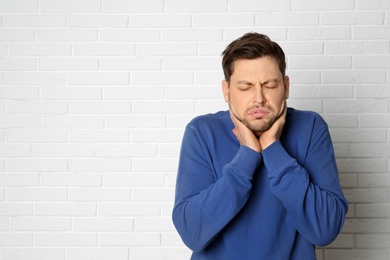 Photo of Man suffering from cough near brick wall. Space for text