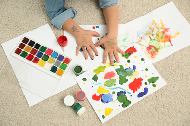 Photo of Little child painting with palms on floor, top view