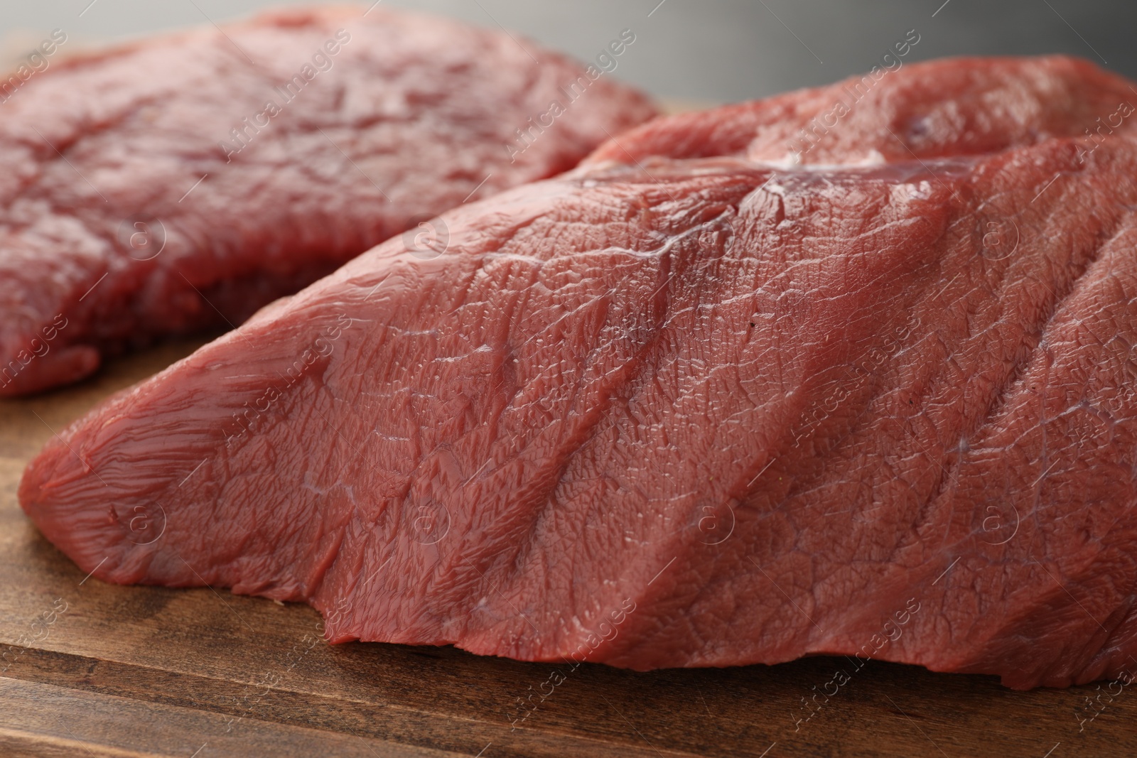 Photo of Pieces of raw beef meat on wooden table, closeup